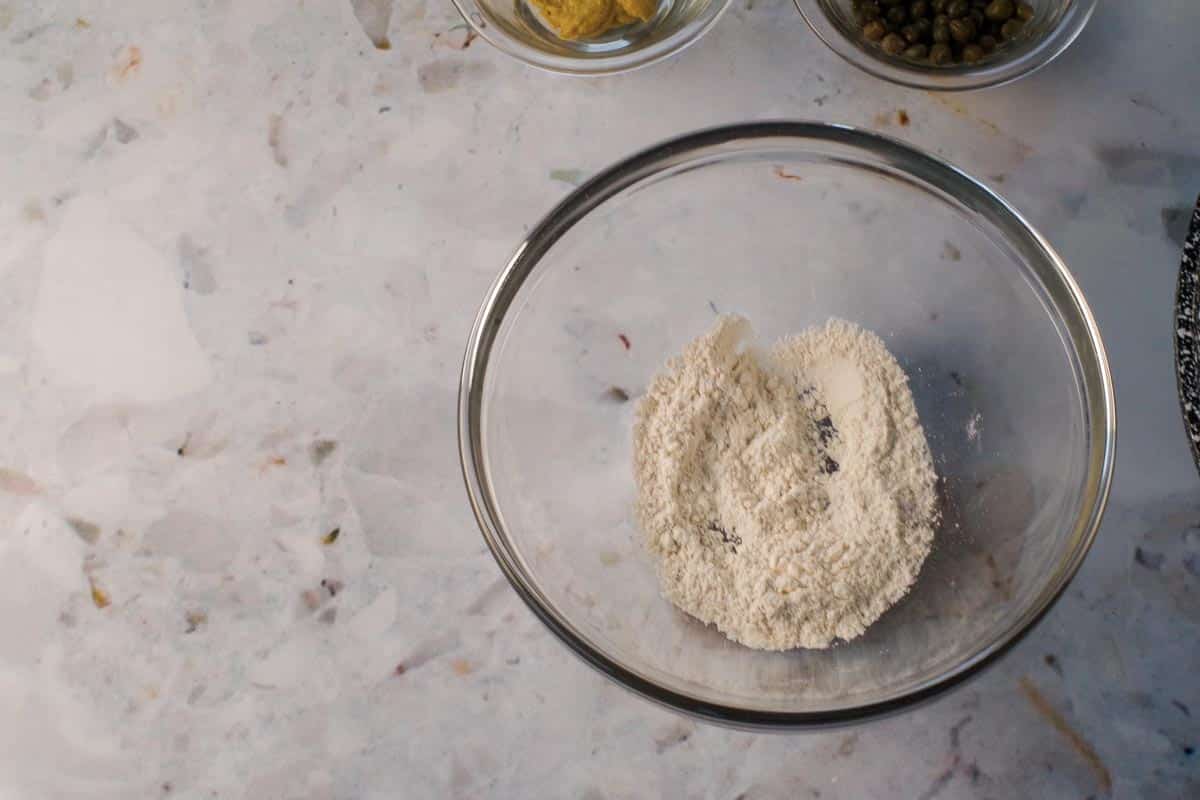 Flour, salt and pepper mixed together in a small glass bowl.