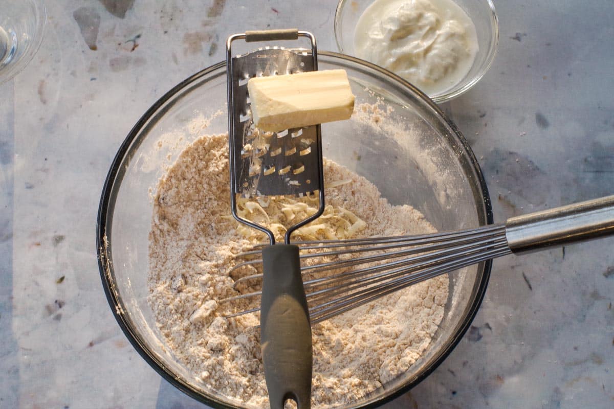 Butter being grated into dry ingredients with grater.