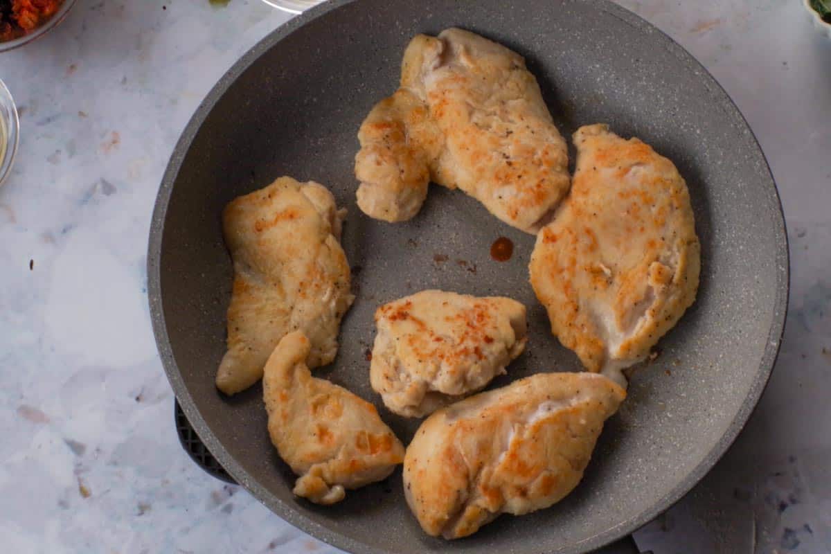 Browned chicken in pan.