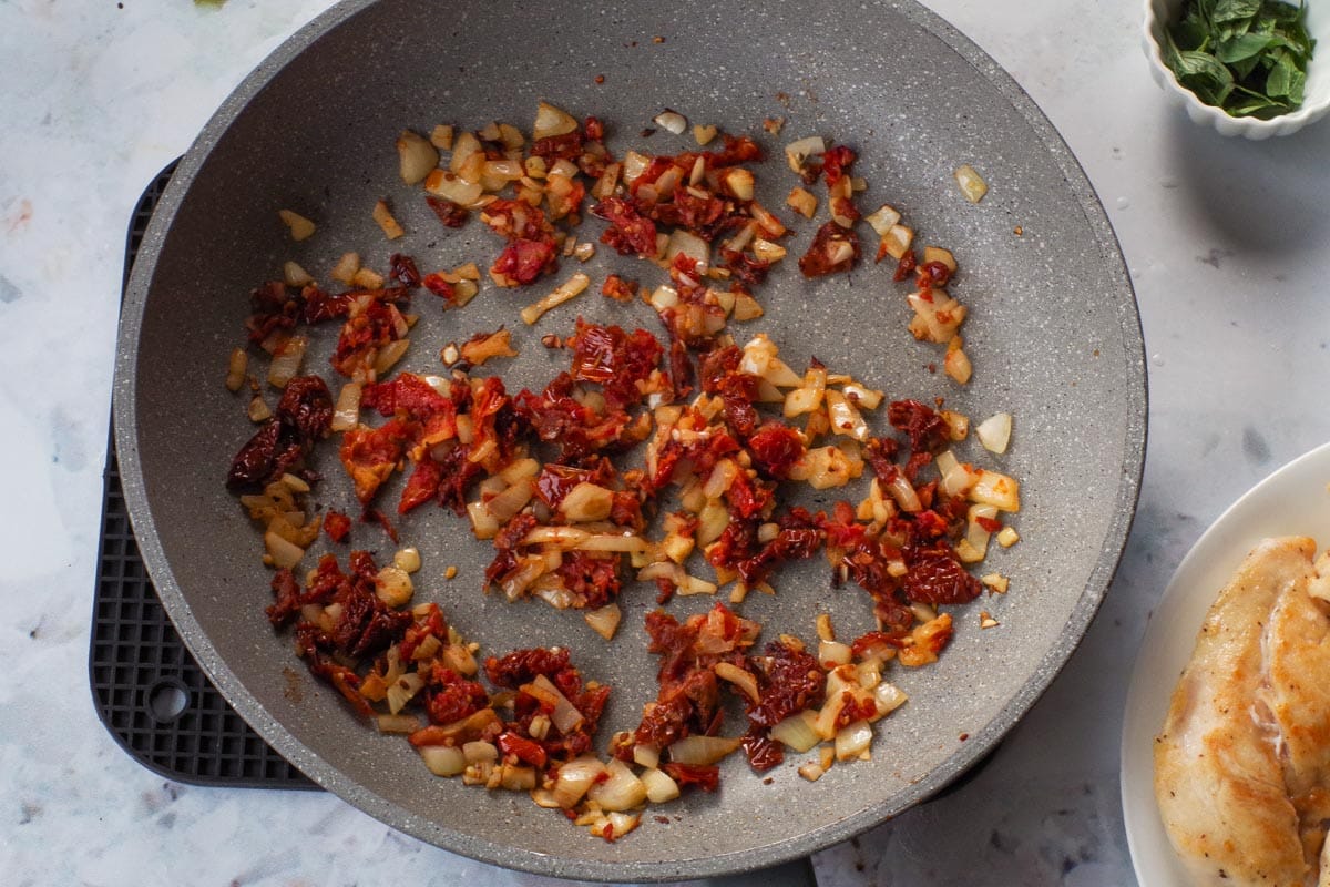 Onions, garlic and tomatoes cooked in pan.