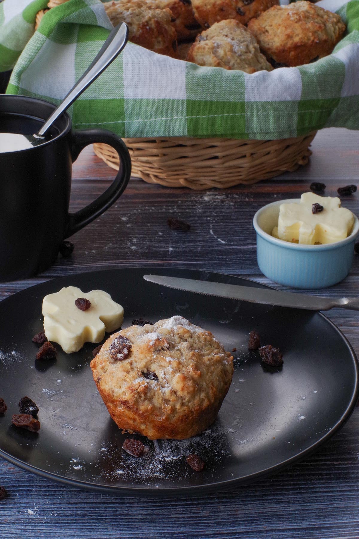 Healthy Irish Soda Bread muffin on a black plate with a shamrock butter on the plate and a knife as well