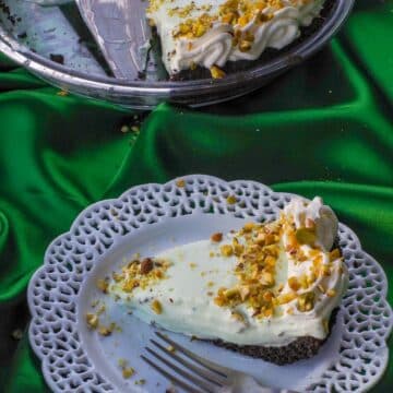 Healthy No Bake Pistachio Mousse Pie on a white plate with more pie in the background