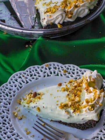 Healthy No Bake Pistachio Mousse Pie on a white plate with more pie in the background