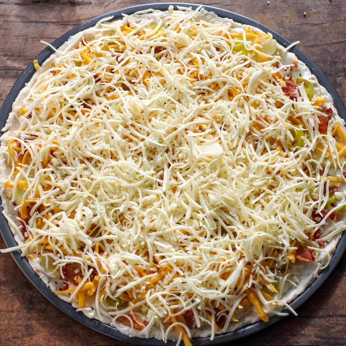 Shredded cheese added to the perogy pizza.