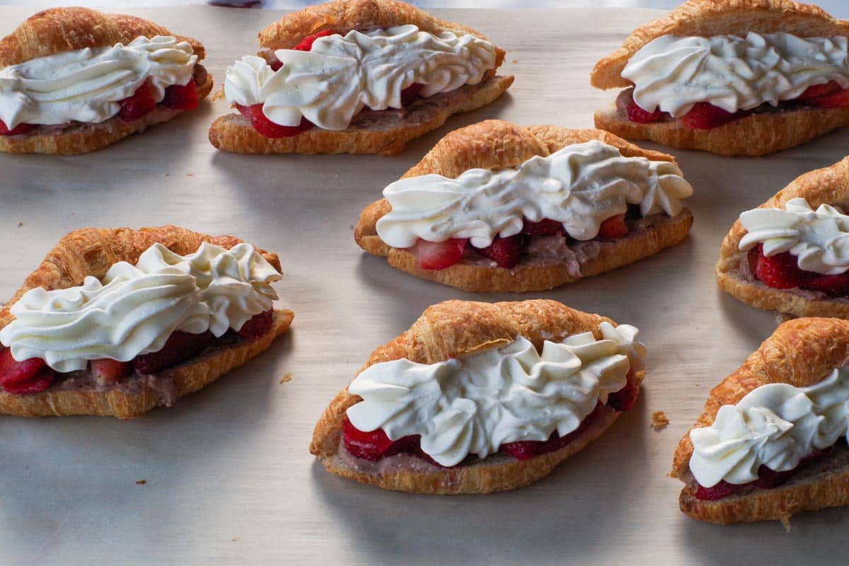 Whipped cream piped onto strawberries in croissants.