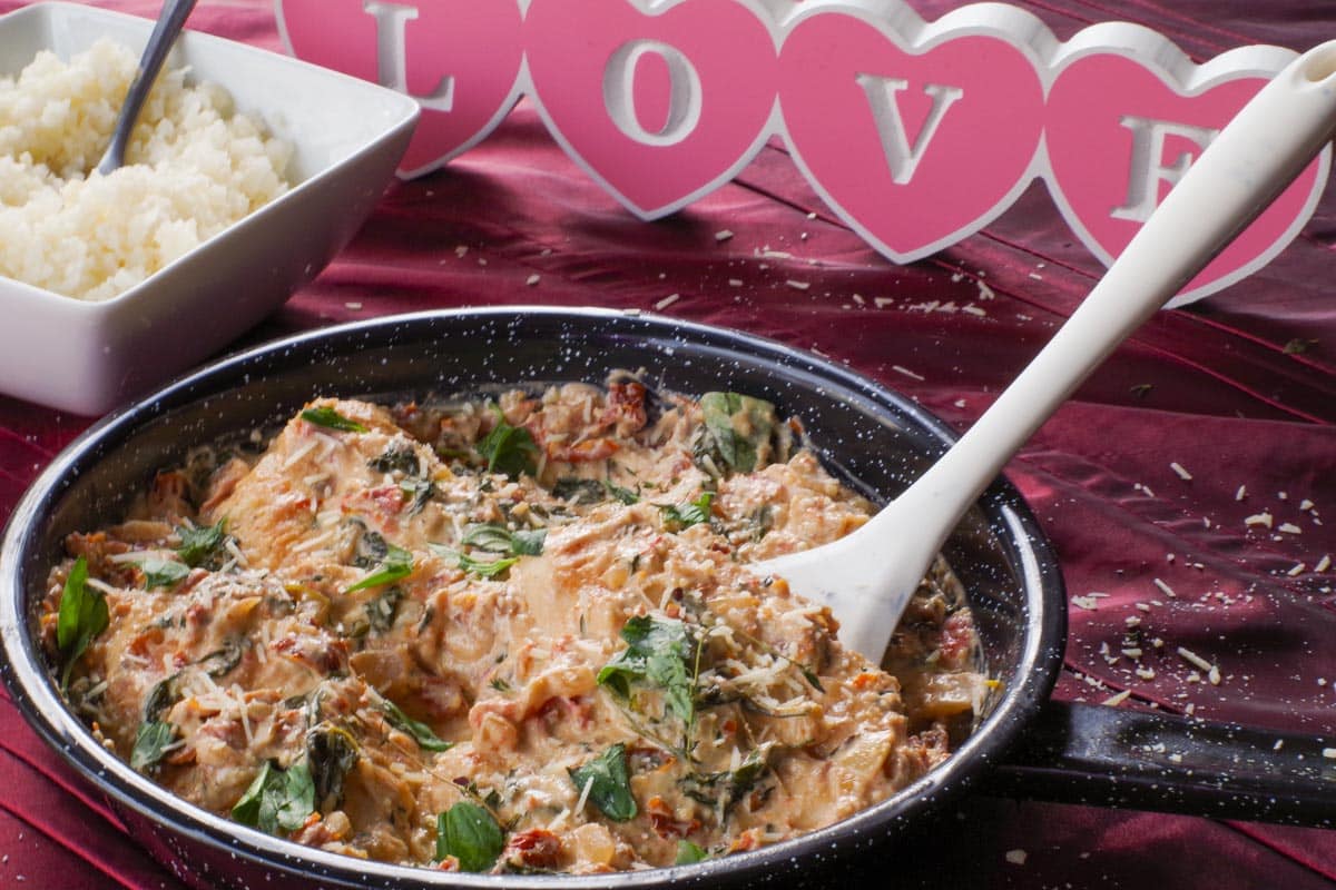 Marry Me Chicken in a pan , with a wooden "Love" sign in the background.