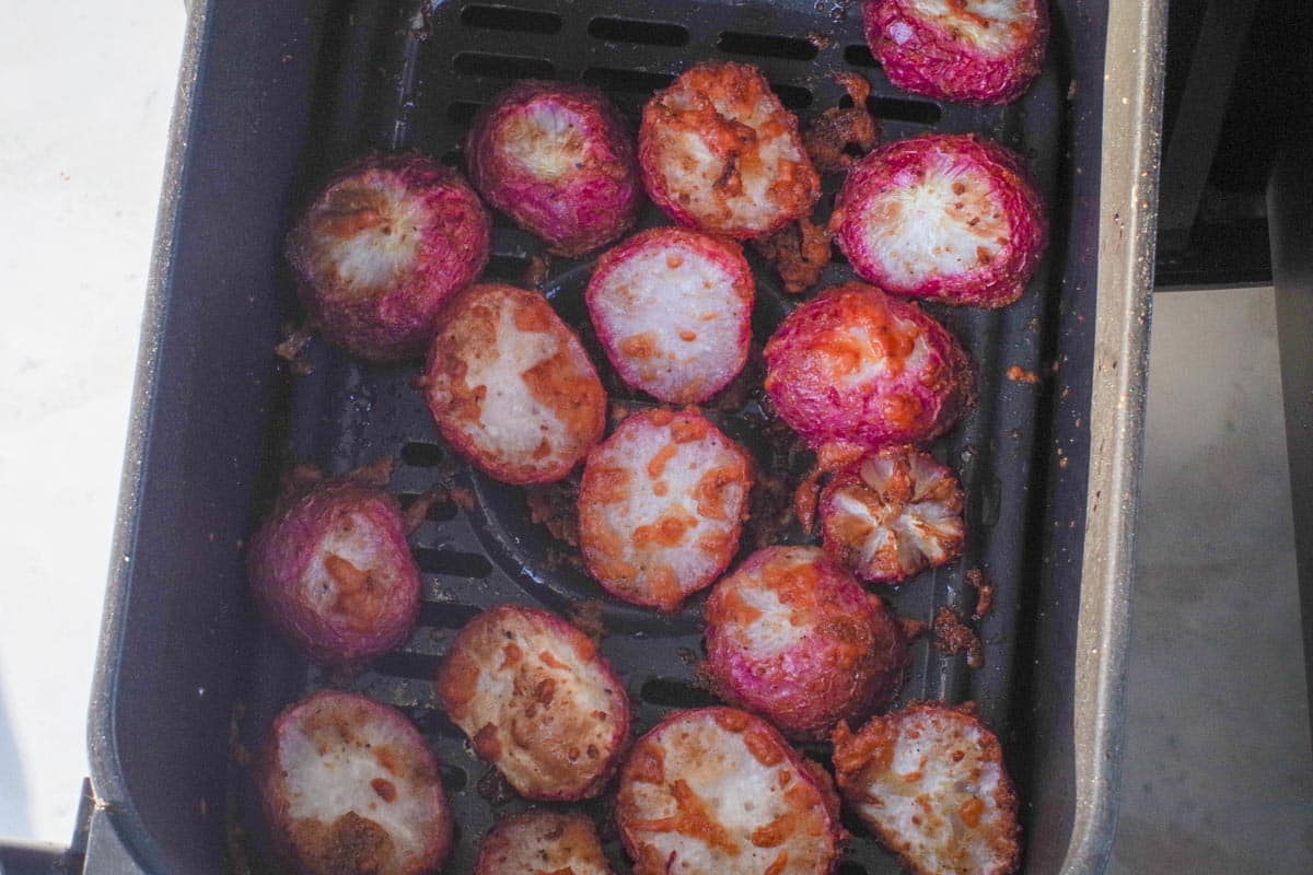 Fully cooked roasted air fryer radishes in an air fryer drawer.