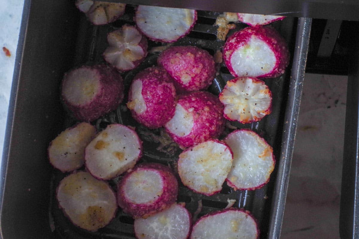 Partly cooked air fryer roasted radishes in an air fryer drawer.