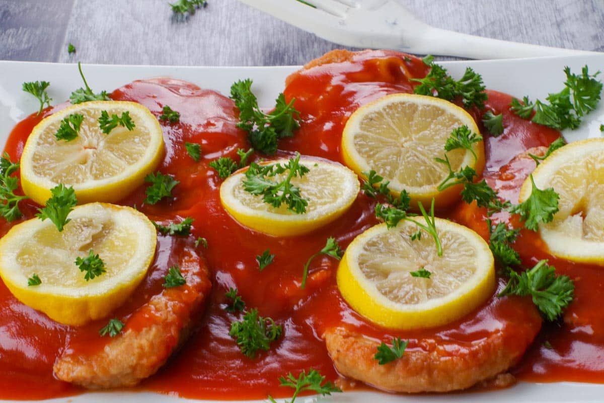 Close-up of Baked Pork Loin in Tangy Sauce on a white platter.