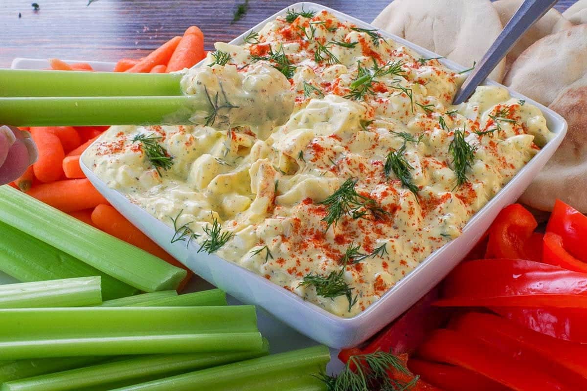 Piece of celery being dipped into deviled egg dip,