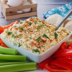 Dill Deviled Egg Dip in the mdidle of a platter of vegetables, with eggs in the background.