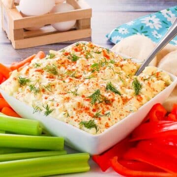 Dill Deviled Egg Dip in the mdidle of a platter of vegetables, with eggs in the background.