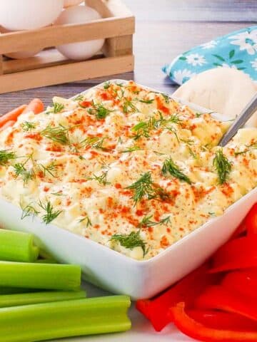 Dill Deviled Egg Dip in the mdidle of a platter of vegetables, with eggs in the background.