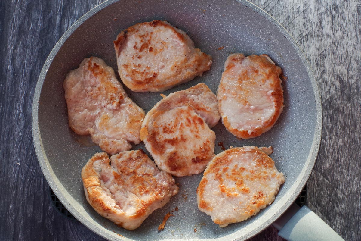 Pork browned on both sides, in frying pan.