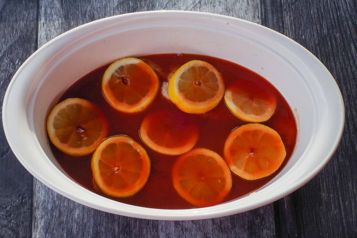 Ketchup mixture poured over the lemon-covered pork in a casserole dish.