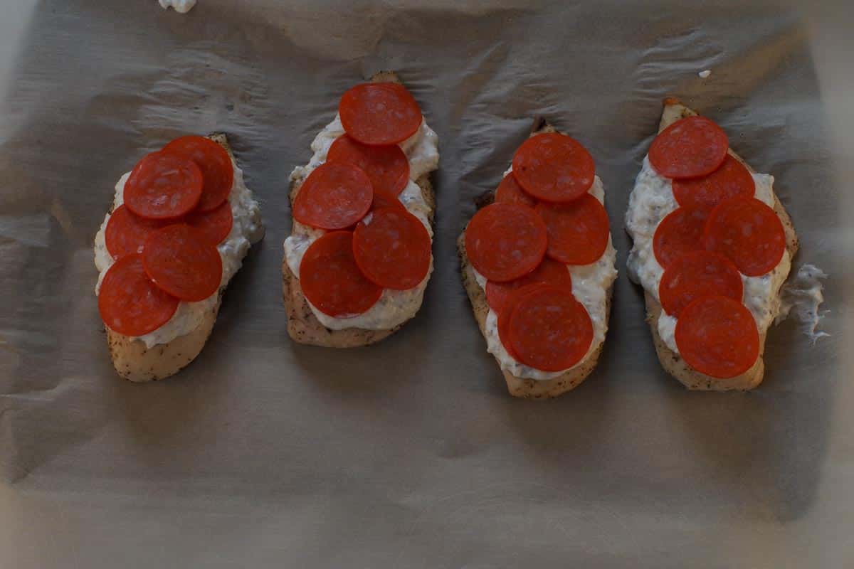 Turkey pepperoni added to chicken breasts, on top of white sauce.