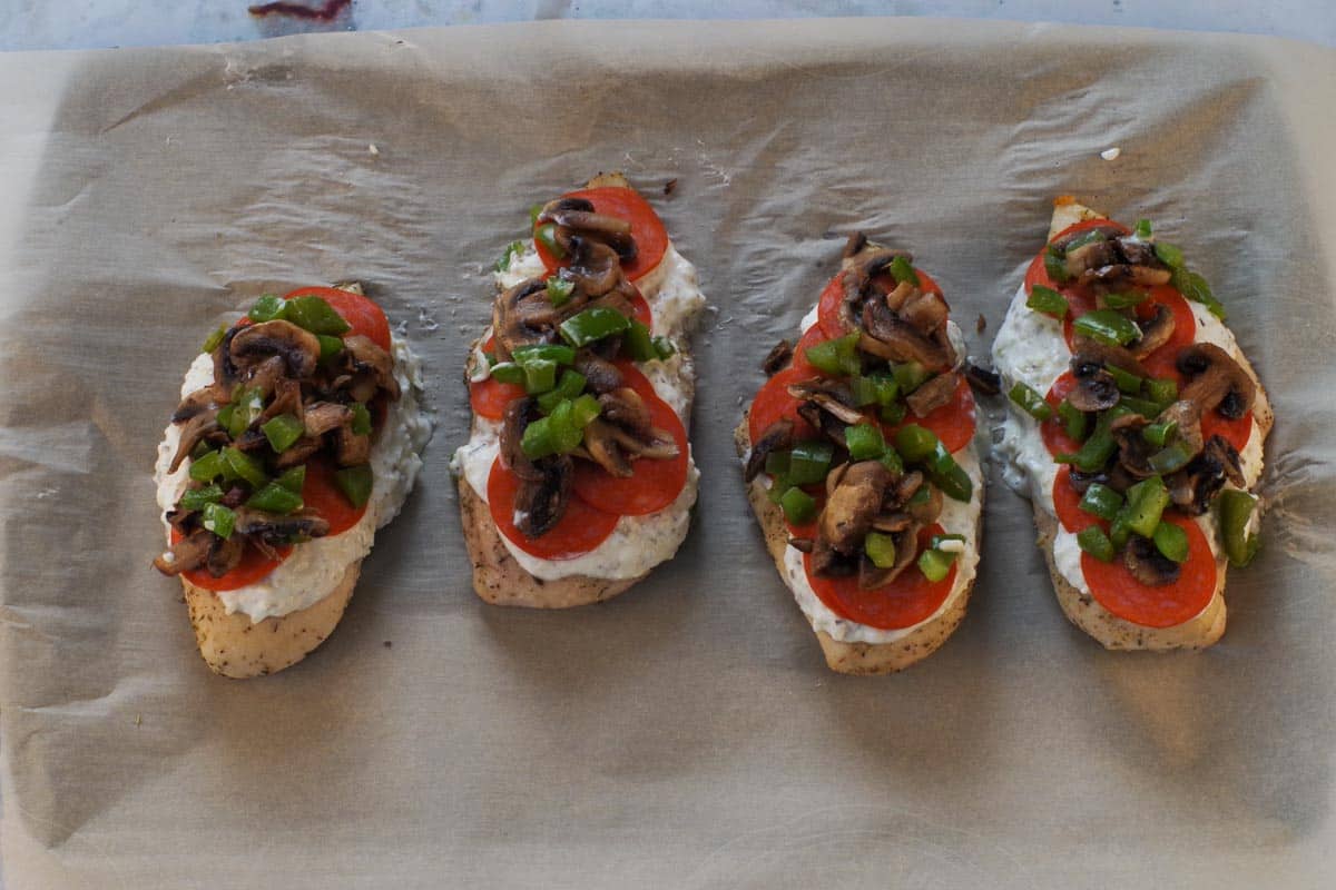 Roasted veggies moved on top of the pepperoni on the chicken, on a parchment lined sheet pan.