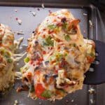 Healthy Sheet Pan Pizza Chicken being lifted off a sheet pan with a black spatula.