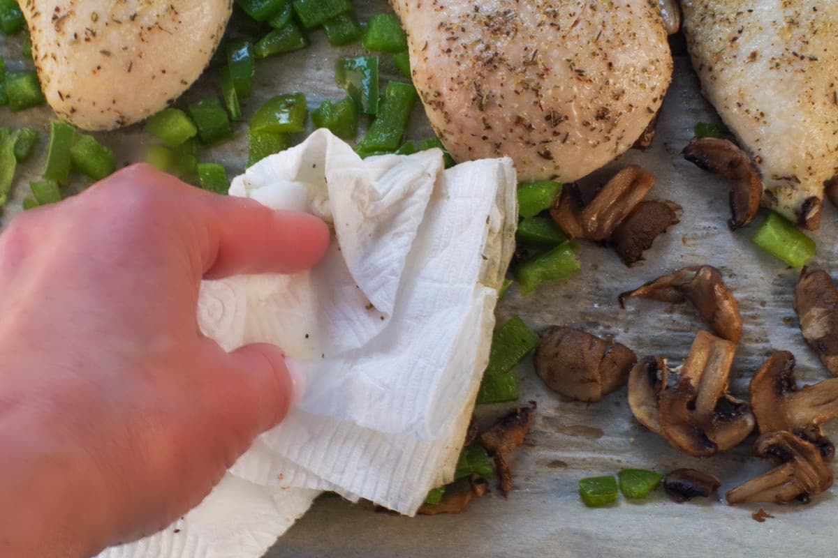 Excess liquid on sheet pan being mopped up with paper towels.