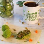 Matcha pistachio energy bites on a piece of parchment paper with a cup of coffee in the background,