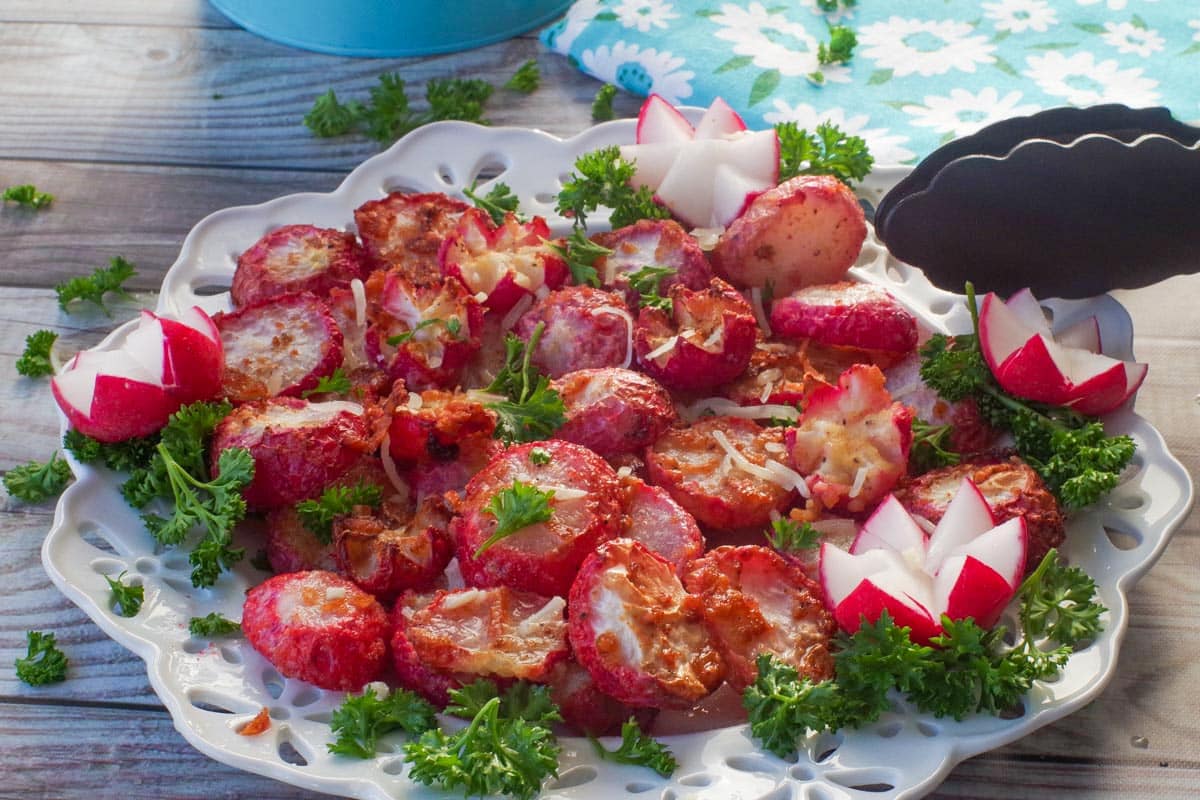 Roasted radishes made in the air fryer on a white plate with air fryer tongs leaning on the plate.