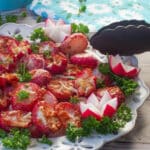 Roasted radishes made in the air fryer on a white plate with air fryer tongs leaning on the plate.