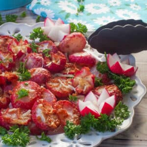 Roasted radishes made in the air fryer on a white plate with air fryer tongs leaning on the plate.