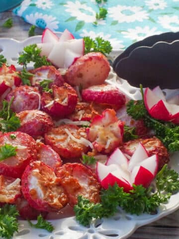 Roasted radishes made in the air fryer on a white plate with air fryer tongs leaning on the plate.