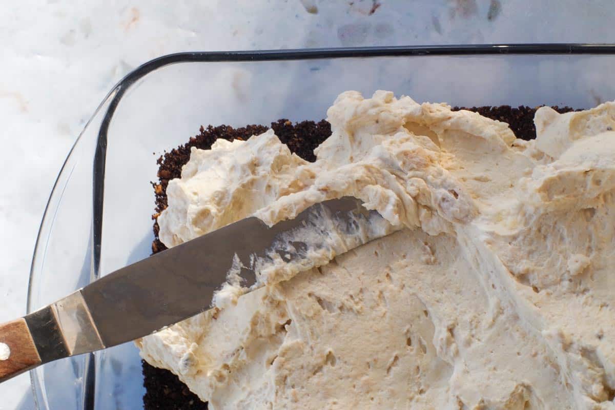 Offset spatula spreading the filling out towards the edges.