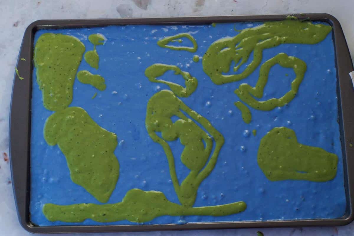 Green matcha batter outlines of continents on the blue to look like a world map.