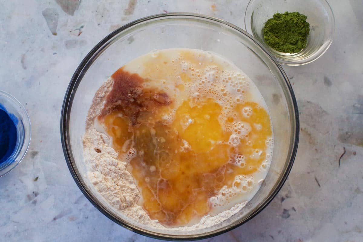 Vanilla extract, milk and butter added with egg to dry ingredients in glass bowl