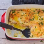 Eggs Benedict Casserole with 2 pieces missing and a spatula lifting a pieces out.