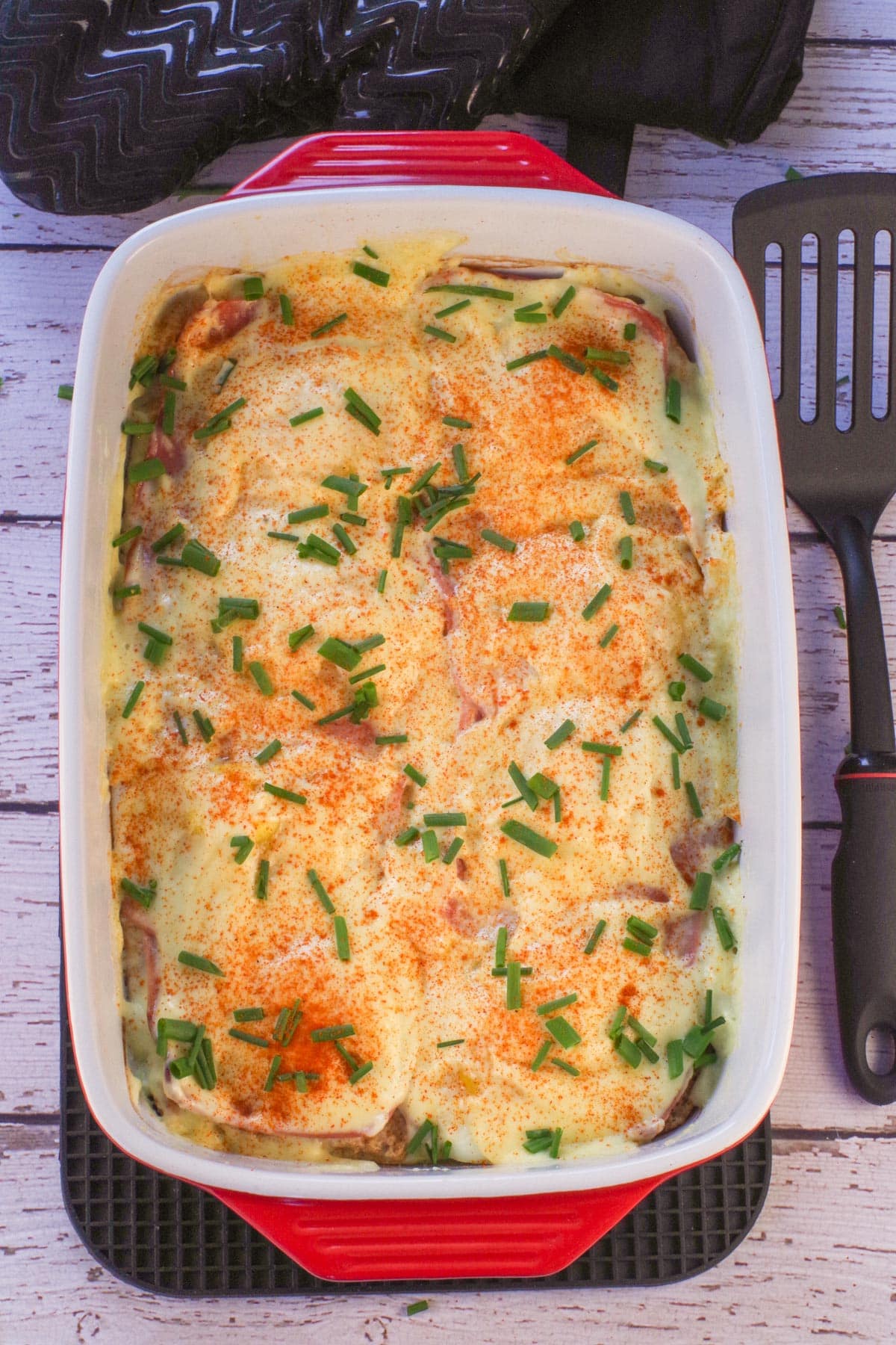 A whole Eggs Benedict Bake with a spatula on the side.