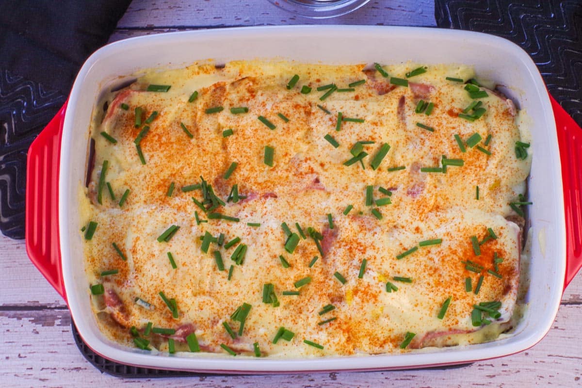 Eggs Benedict Bake with Hollandise sauce and garnishes.