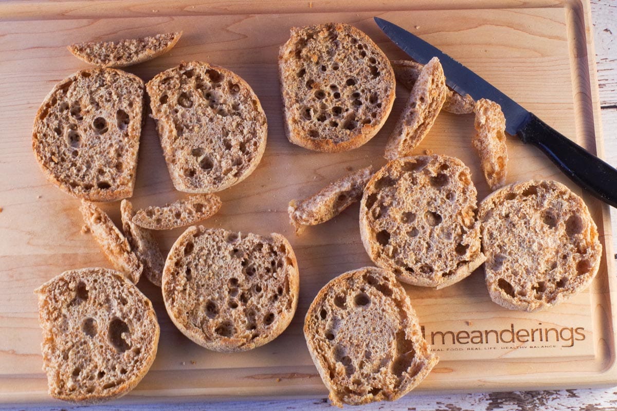 English Muffins halves on a cutting board with a little cut off each half, to fit in casserole dish.