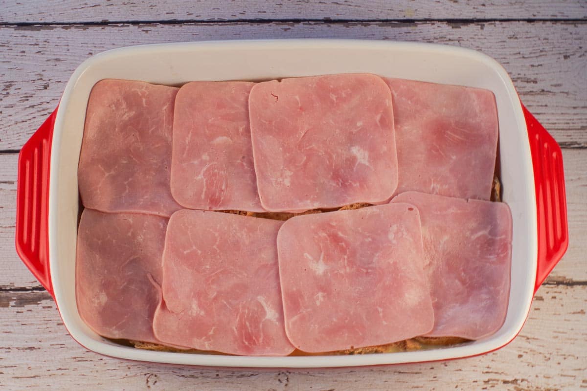 Ham slices on top of English muffins in casserole dish.