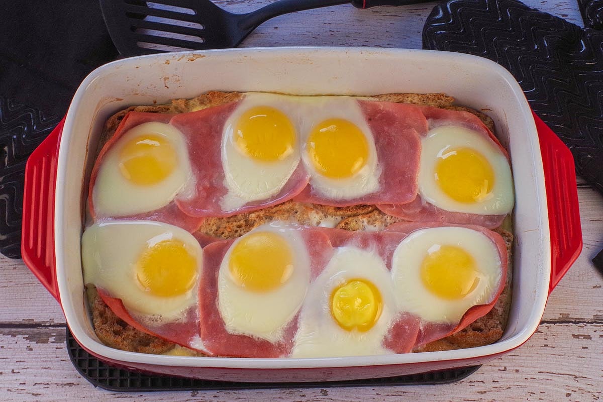 Baked eggs on top of ham in casserole dish.