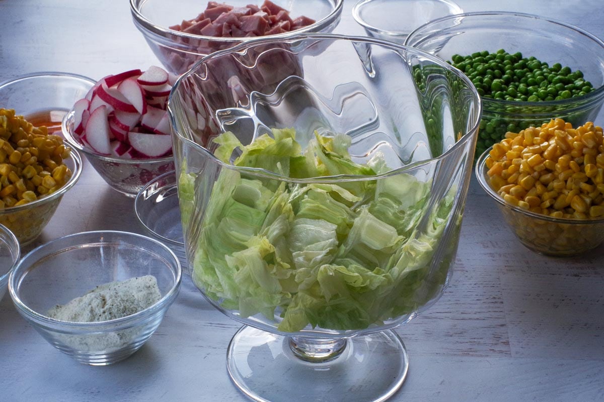Lettuce added as first layer in glass bowl in Layered Leftover Ham Salad.