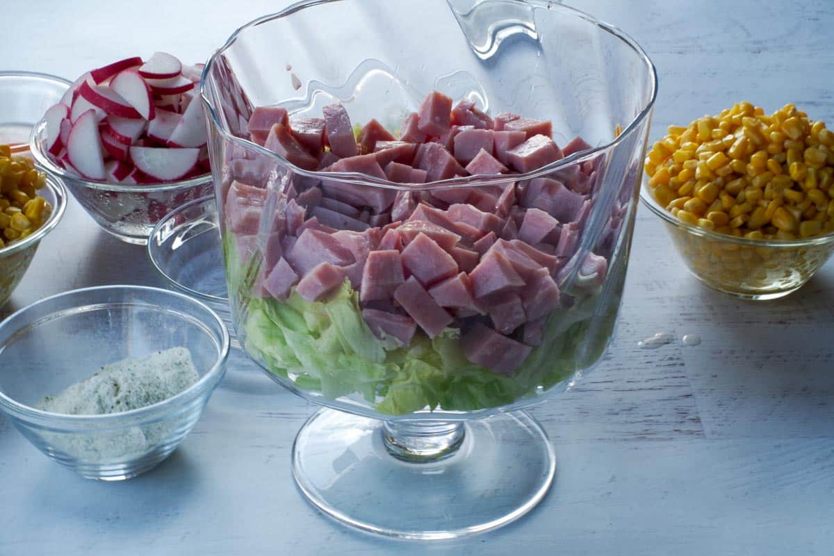 Ham added as second layer in glasss trifle bowl in Layered Leftover Ham Salad.
