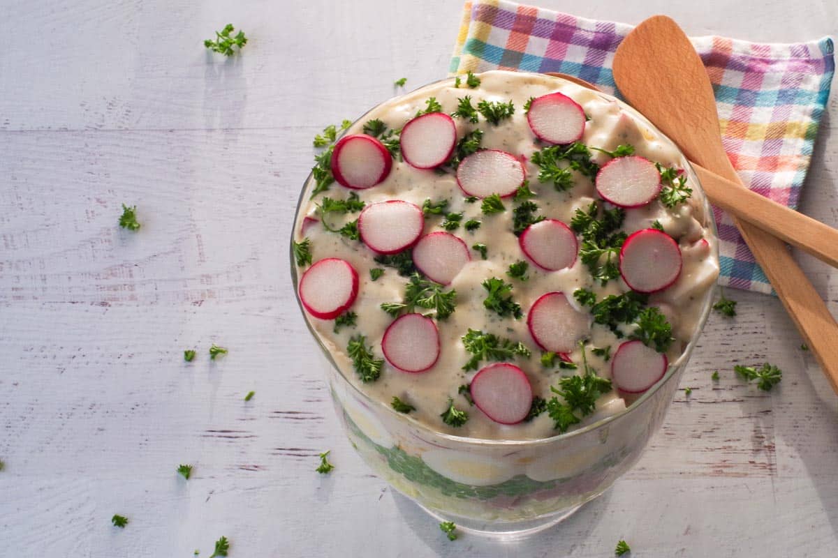 Dresssing and radish slices added to the top of the salad with parsley.