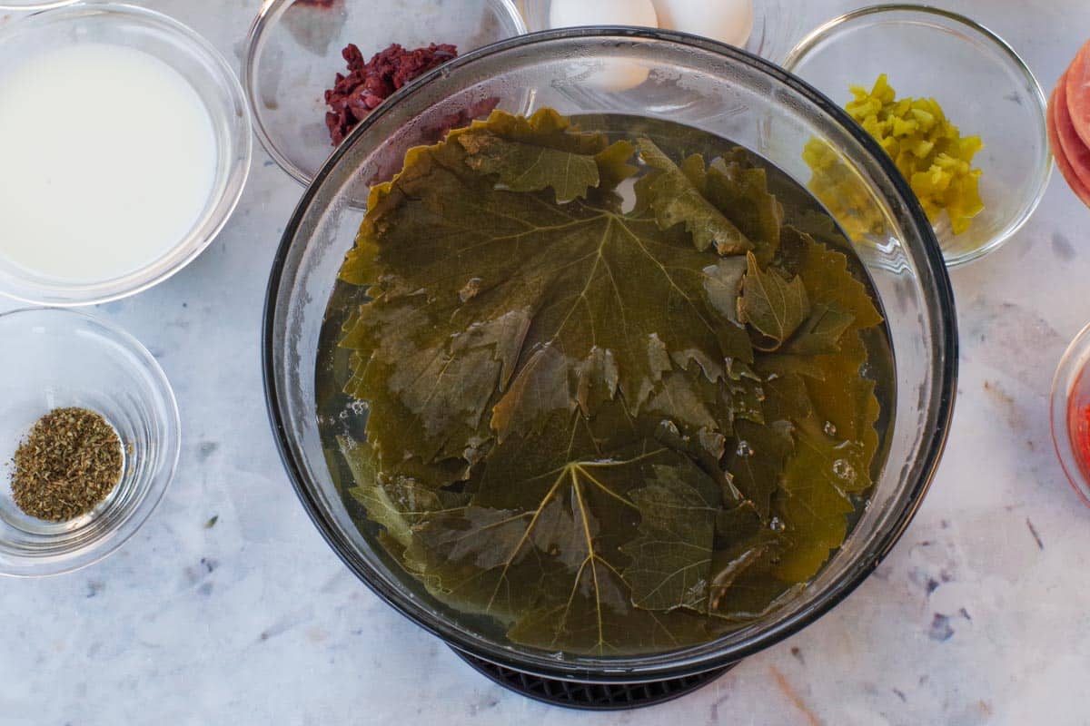 Grape leaves in hot water in a large glass bowl.