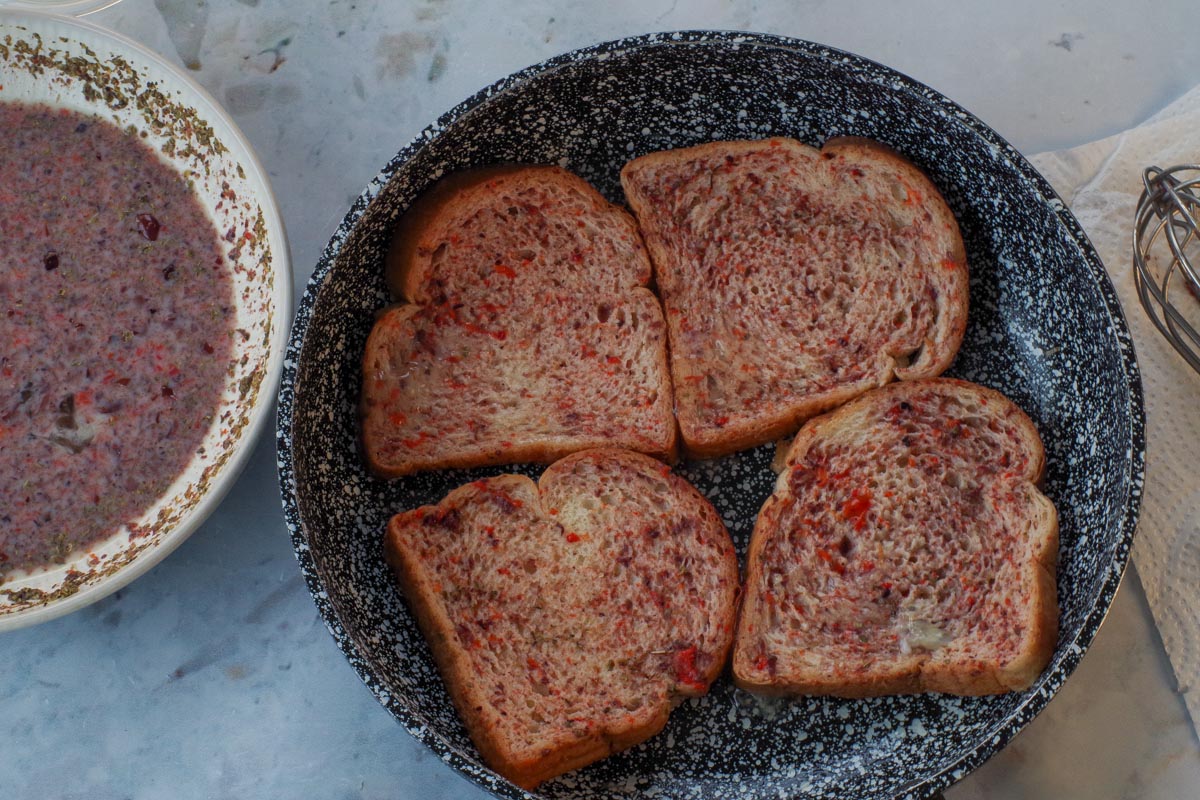 Bread in a pre-heated frying pan after being dredged in mixture.