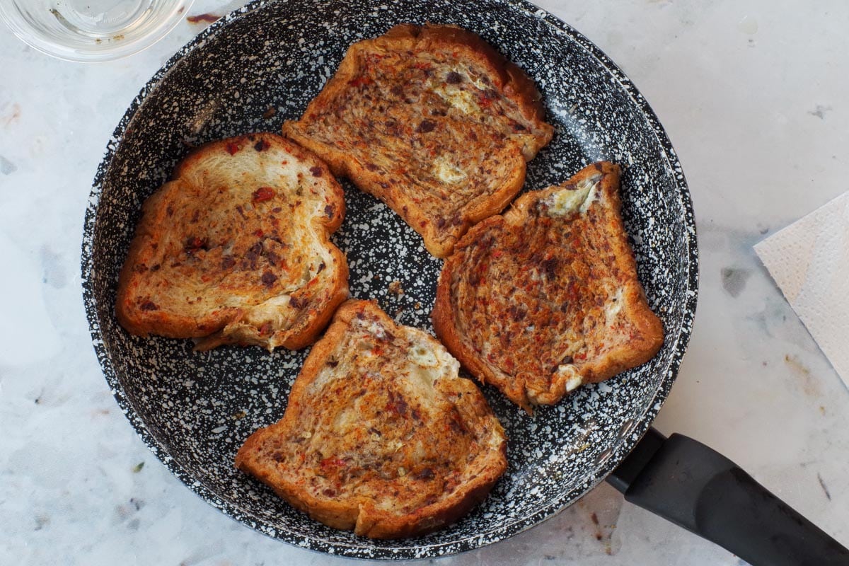 Coated bread cooked in frying pan.