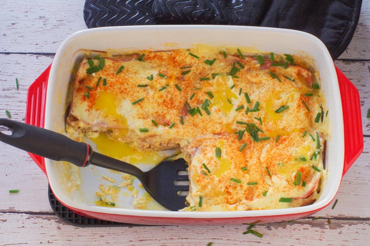 Eggs Benedict Casserole with 2 pieces missing an a piece being lifted out with a spatula.