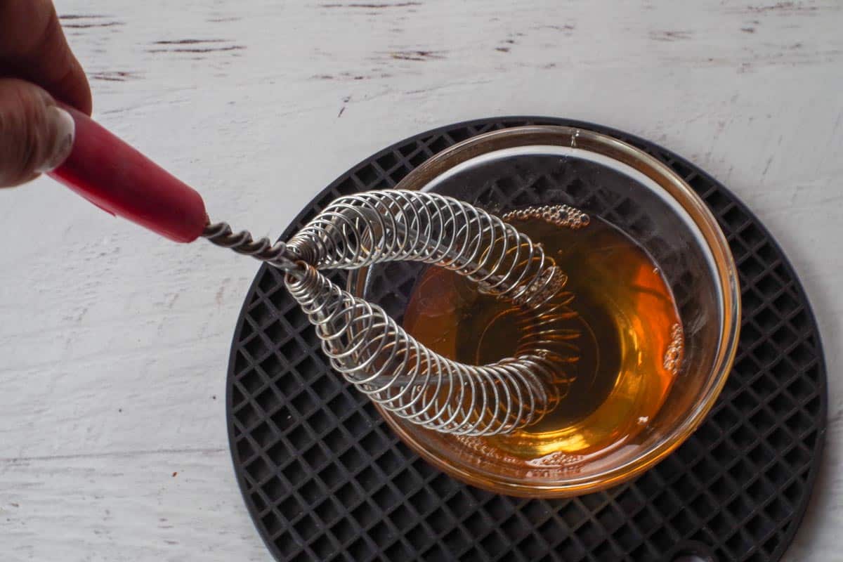 Honey, water and vanilla extract mixed together in small glass bowl with whisk.