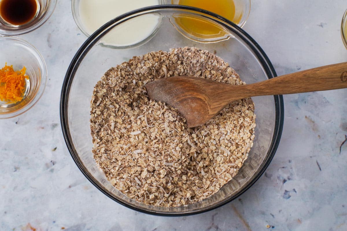 Dry ingredients mixed together in a large glass bowl with a wooden spoon,