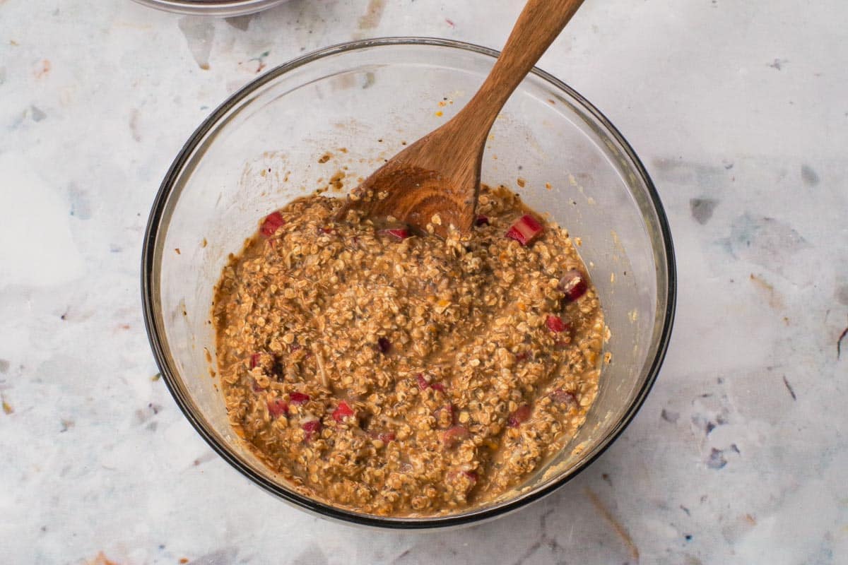 Wet and dry ingredients mixed together in a large glass bowl with wooden spoon
