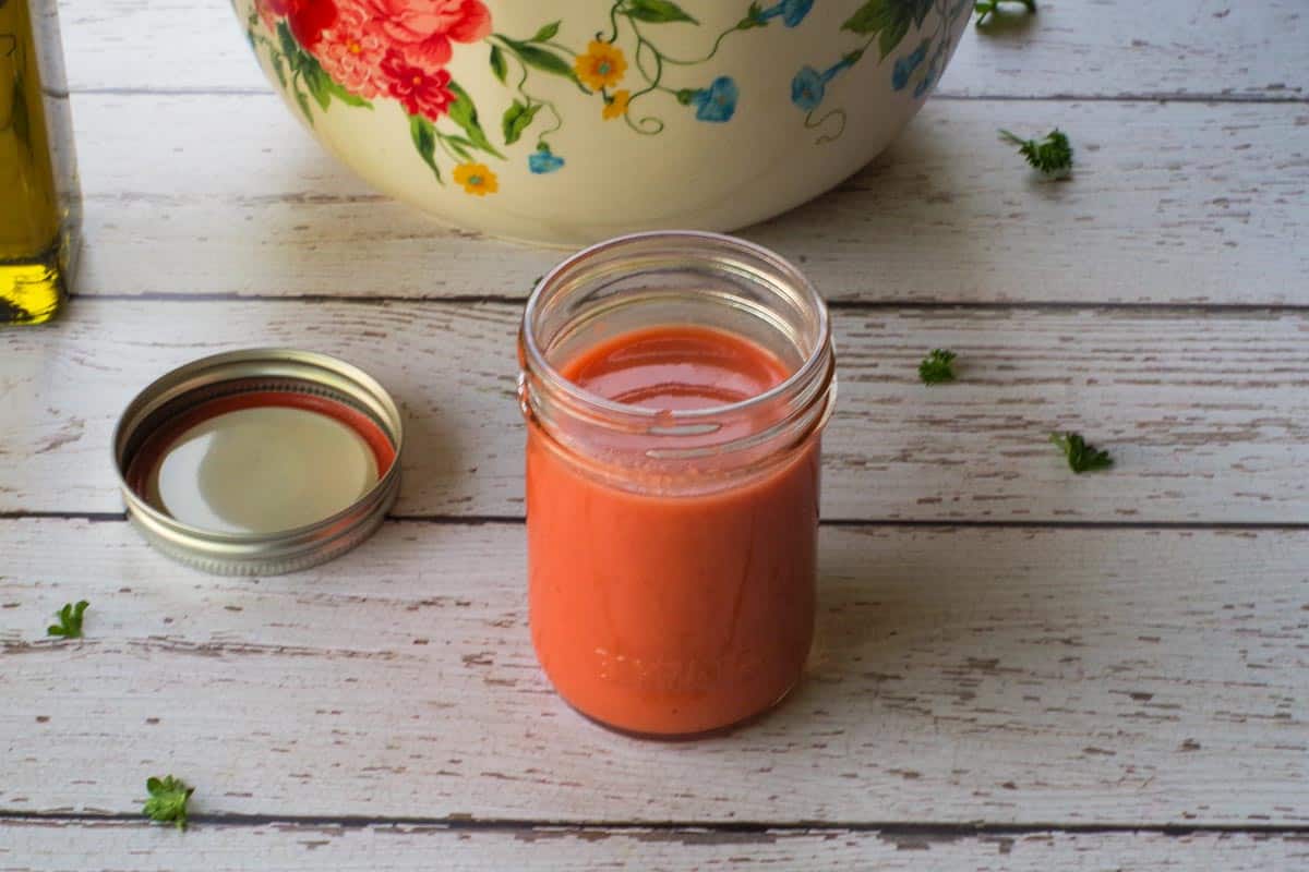 Rhubarb Vinaigrette in a jar with a flowered salad bowl in the background.