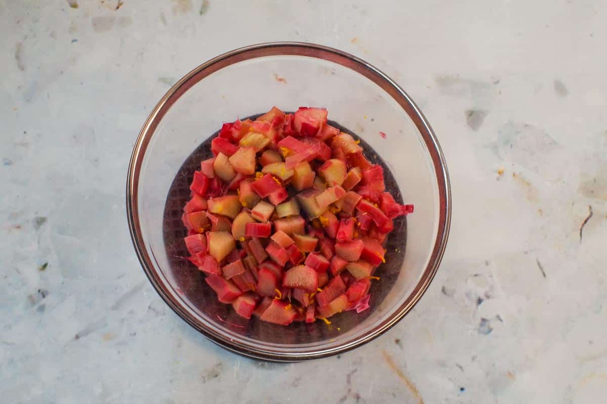 Cooked rhubarb with lemon juice and orange zest in a glass bowl.