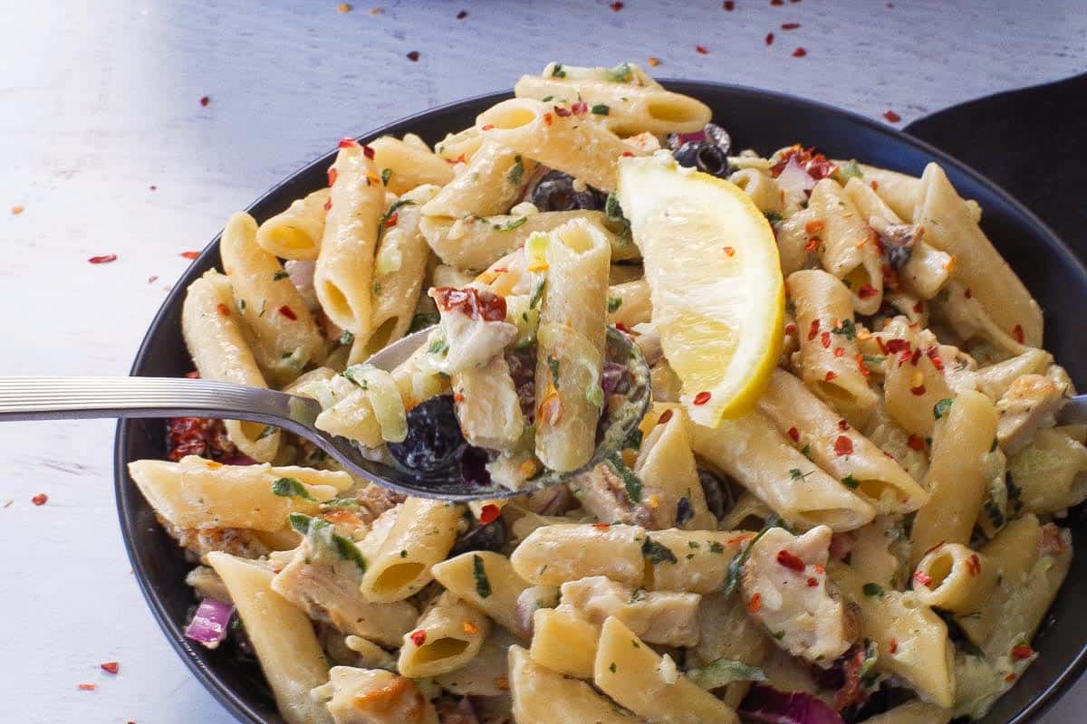 A spoonful of creamy Tzatziki pasta with chicken and olives.